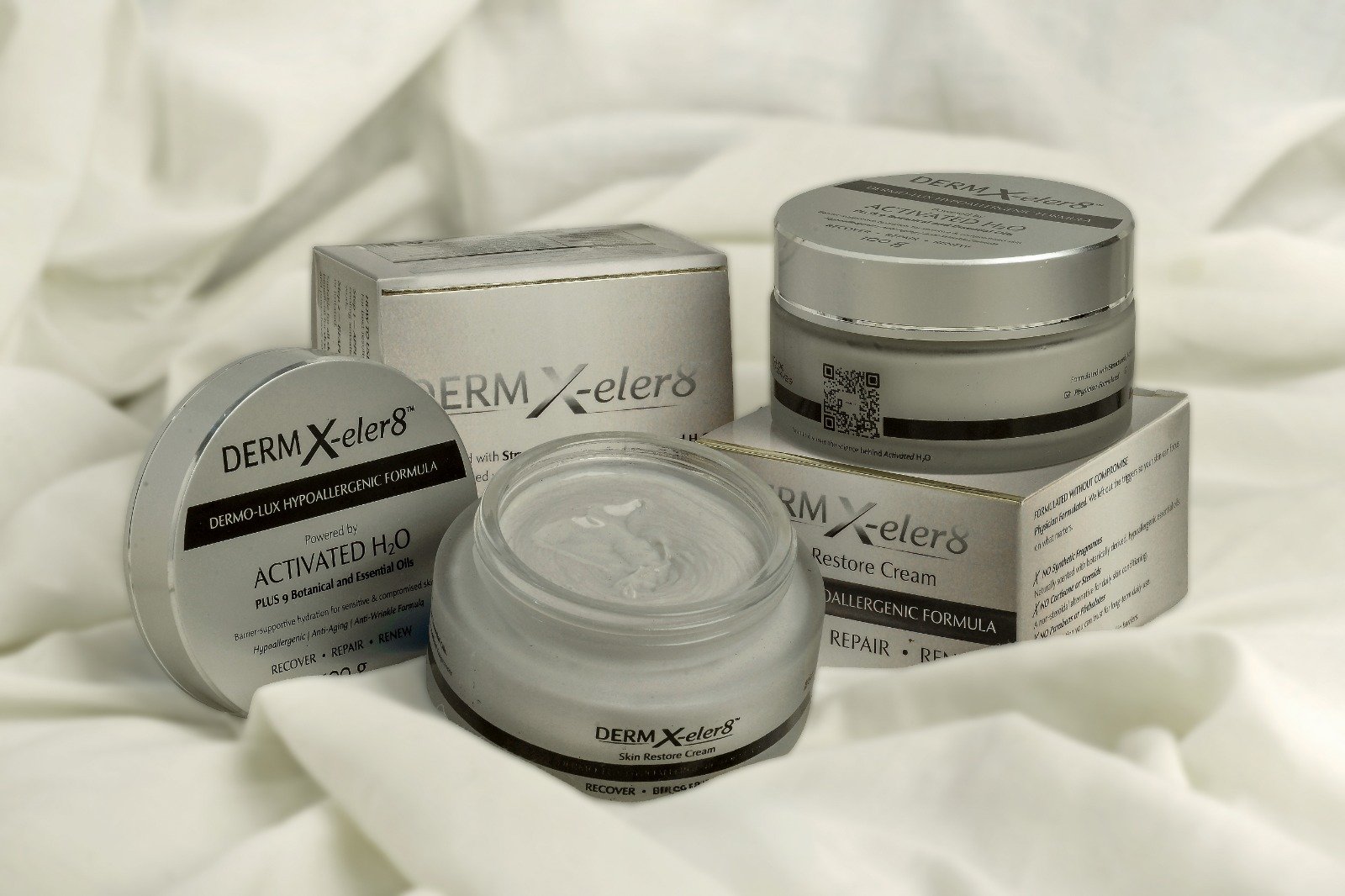 Derm X-eler8 jars and boxes on white silk fabric